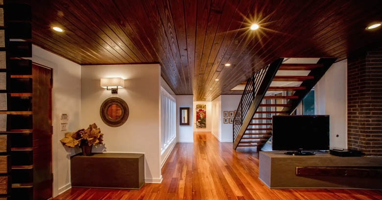 A modern entry way with antique heart pine beam staircase, wood ceiling, and rustic oak flooring.