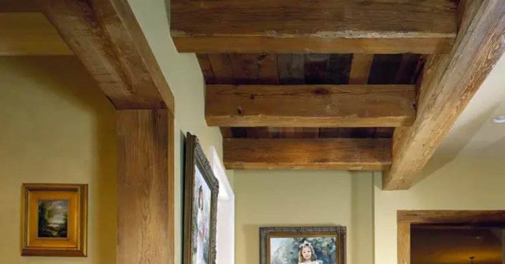 Strikingly large antique heart pine beams offer a robust viewpoint in this rustic hallway.
